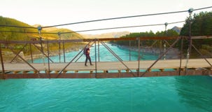 Mid-air πτήση πέρα από τον περίπατο τουριστών νεαρών άνδρων πέρα από μια γέφυρα αναστολής απόθεμα βίντεο Mid-air πτήση πέρα από τον περίπατο τουριστών νεαρών άνδρων πέρα από μια γέφυρα αναστολής απόθεμα βίντεο
