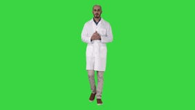 Middenleeftijd artsenmens die het medische eenvormige voorstellen dragen en met palm van hand richten die de camera op Green beki stock video Middenleeftijd artsenmens die het medische eenvormige voorstellen dragen en met palm van hand richten die de camera op Green beki stock video