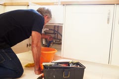 Middle aged male plumber fixing a kitchen sink royalty free stock photo Middle aged male plumber fixing a kitchen sink royalty free stock photo