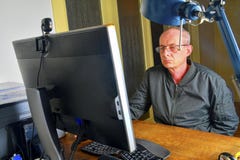 Middle aged man with glasses sitting at desk. Mature man using personal computer. Senior concept. Man working at office stock images Middle aged man with glasses sitting at desk. Mature man using personal computer. Senior concept. Man working at office stock images