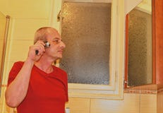 Middle aged man shaving in a bathroom, using electric razor. Senior concept. Mature man at home stock image Middle aged man shaving in a bathroom, using electric razor. Senior concept. Mature man at home stock image