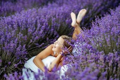 A middle-aged woman lies in a lavender field and enjoys aromatherapy. Aromatherapy concept, lavender oil, photo session. In lavender