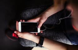 A midsection of young girl or woman with earphones and smartphone in a gym. stock image A midsection of young girl or woman with earphones and smartphone in a gym. stock image