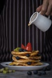 Miel de versement de chef sur des crêpes images stock Miel de versement de chef sur des crêpes images stock