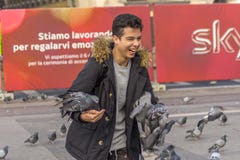 Milan, Italie 23-11-2017 Jeune homme heureux avec des pigeons dans la place devant Milan Cathedral Di Milan de Duomo image stock Milan, Italie 23-11-2017 Jeune homme heureux avec des pigeons dans la place devant Milan Cathedral Di Milan de Duomo image stock