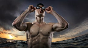 Milieux de sport Jeune position sportive de nageur près de la rivière de coucher du soleil photo stock Milieux de sport Jeune position sportive de nageur près de la rivière de coucher du soleil photo stock