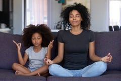 Mindful african mom with funny kid daughter doing yoga together