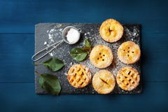 Mini apple pies decorated sugar powder on blue table from above. Delicious autumn pastry dessert. royalty free stock image Mini apple pies decorated sugar powder on blue table from above. Delicious autumn pastry dessert. royalty free stock image