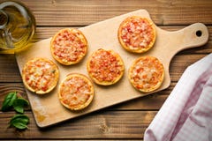 Mini pizza en tabla de cortar Imagen de archivo libre de regalías Mini pizza en tabla de cortar Imagen de archivo libre de regalías