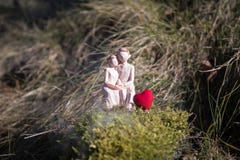Miniatura del mujeres y un hombre en el amor que se sienta en banco de la muestra del corazón con el copyspace ligero del bokeh, foto de archivo Miniatura del mujeres y un hombre en el amor que se sienta en banco de la muestra del corazón con el copyspace ligero del bokeh, foto de archivo
