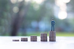 Miniature businessman on stack of coins stock images Miniature businessman on stack of coins stock images