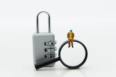 Miniature people: Businessman with a magnifying glass and master key encoding. Image use for background security system Stock Photos Miniature people: Businessman with a magnifying glass and master key encoding. Image use for background security system Stock Photos