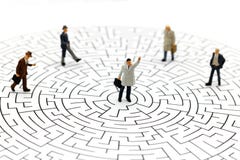 Miniature people: Businessman standing on center of maze. stock photo Miniature people: Businessman standing on center of maze. stock photo