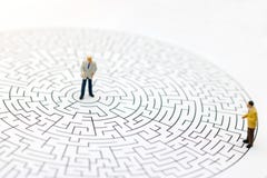 Miniature people: Businessman standing on center of maze. stock photos Miniature people: Businessman standing on center of maze. stock photos
