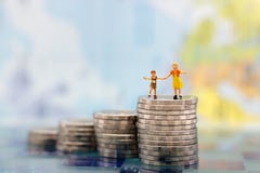 Miniature people: Happy children couple standing on coins stack, money saving growth. Saving Money, Education, Emergency plan stock photo Miniature people: Happy children couple standing on coins stack, money saving growth. Saving Money, Education, Emergency plan stock photo