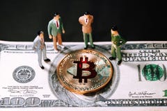 Miniature people small figures businessmen stand and looking Golden bitcoin on one hundred dollar banknote. stock photos Miniature people small figures businessmen stand and looking Golden bitcoin on one hundred dollar banknote. stock photos