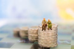 Miniaturowi ludzie, stara pary postaci pozycja na górze stert monet Wizerunku use dla tło emerytura planowania, zdjęcie stock Miniaturowi ludzie, stara pary postaci pozycja na górze stert monet Wizerunku use dla tło emerytura planowania, zdjęcie stock