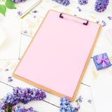 Minimalistic workspace with clipboard, envelope, pen, lilac flowers and box on white background. Flat lay, top view. Freelancer or Stock Photography Minimalistic workspace with clipboard, envelope, pen, lilac flowers and box on white background. Flat lay, top view. Freelancer or Stock Photography