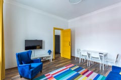 MINSK, BELARUS - March, 2019: retro bright interior of hipster flat apartments with blue sofa, yellow door and colored carpet stock photography MINSK, BELARUS - March, 2019: retro bright interior of hipster flat apartments with blue sofa, yellow door and colored carpet stock photography