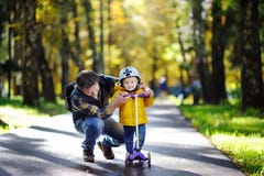 Mittelaltervater, der seinem Kleinkindsohn zeigt, wie man einen Roller in einem Herbstpark reitet stockfotografie Mittelaltervater, der seinem Kleinkindsohn zeigt, wie man einen Roller in einem Herbstpark reitet stockfotografie