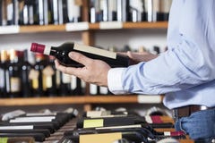 Mittelteil des Kunden Rotwein-Flasche halten lizenzfreie stockbilder Mittelteil des Kunden Rotwein-Flasche halten lizenzfreie stockbilder