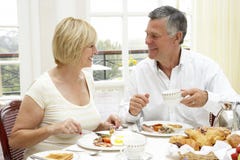 Mittlere gealterte Paare, die Hotel-Frühstück genießen lizenzfreies stockfoto Mittlere gealterte Paare, die Hotel-Frühstück genießen lizenzfreies stockfoto