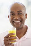 Mittlerer gealterter Mann, der frischen Orangensaft trinkt lizenzfreies stockbild Mittlerer gealterter Mann, der frischen Orangensaft trinkt lizenzfreies stockbild