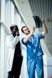 Mixed race medical doctors. Two male doctors reviewing x-ray in hospital corridor stock photography Mixed race medical doctors. Two male doctors reviewing x-ray in hospital corridor stock photography