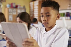 Mixed race primary school boy using tablet computer in class royalty free stock images Mixed race primary school boy using tablet computer in class royalty free stock images