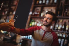 Mjukt geende exponeringsglas för kvinnlig stång av coctailen till kunden royaltyfria foton Mjukt geende exponeringsglas för kvinnlig stång av coctailen till kunden royaltyfria foton