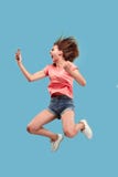 Full length of pretty young woman with mobile phone while jumping Royalty Free Stock Images Full length of pretty young woman with mobile phone while jumping Royalty Free Stock Images
