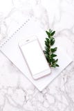 Mobile phone and white notebook on a marble background with greens royalty free stock image Mobile phone and white notebook on a marble background with greens royalty free stock image