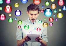 Mobile technology high tech concept. Amazed man using tablet computer with social media application icons flying out of screen royalty free stock images Mobile technology high tech concept. Amazed man using tablet computer with social media application icons flying out of screen royalty free stock images