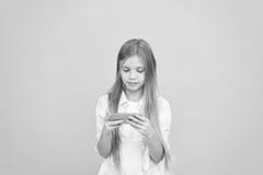 Mobilna gad?et zale?no?? Dziewczyny ma?ego dziecka chwyta u?miechni?ty smartphone Internetowy surfing i og?lnospo?eczne sieci Pro zdjęcia stock Mobilna gad?et zale?no?? Dziewczyny ma?ego dziecka chwyta u?miechni?ty smartphone Internetowy surfing i og?lnospo?eczne sieci Pro zdjęcia stock