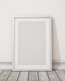 Mock up blank white picture frame on the white wall and the wooden floor, background