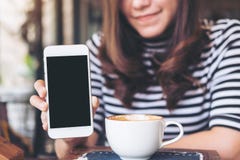 Mockup Image Of A Beautiful Woman Holding And Showing White Mobile Phone With Blank Black Screen With Smiley Face And Coffee Cup O Stock Images