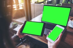Mockup Image Of A Businesswoman Holding White Mobile Phone , Black Tablet And Laptop With Blank Green Screen On Vintage Wooden Tab Stock Photos