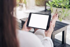 Mockup image of a woman sitting and holding black tablet pc with blank white desktop screen , feeling relaxed with sand and beach stock image Mockup image of a woman sitting and holding black tablet pc with blank white desktop screen , feeling relaxed with sand and beach stock image