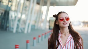 Moda model w czerwonych okularach przeciwsłonecznych chodzi ufnego wzdłuż ulicznego pobliskiego centrum handlowego młodzi dorośli zbiory Moda model w czerwonych okularach przeciwsłonecznych chodzi ufnego wzdłuż ulicznego pobliskiego centrum handlowego młodzi dorośli zbiory