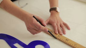 Modeformgivare som arbetar på tabellen Hand av den kvinnliga skräddareteckningsmodellen på papper i hennes studio kvinnlig skrädd Modeformgivare som arbetar på tabellen Hand av den kvinnliga skräddareteckningsmodellen på papper i hennes studio kvinnlig skrädd