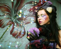 model with creative make-up blowing soap bubbles.