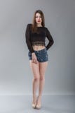Modelo consideravelmente 'sexy' da mulher com corpo surpreendente, pés longos, short azul vestindo da sarja de Nimes, parte super foto de stock Modelo consideravelmente 'sexy' da mulher com corpo surpreendente, pés longos, short azul vestindo da sarja de Nimes, parte super foto de stock