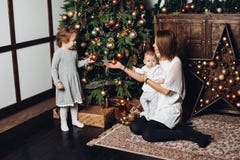 Moder med två ungar på julgranen royaltyfri bild Moder med två ungar på julgranen royaltyfri bild