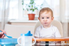 Modermatning behandla som ett barn rymma ut hennes hand med en sked av havregröt i köket Sinnesrörelser av ett barn, medan äta royaltyfri foto Modermatning behandla som ett barn rymma ut hennes hand med en sked av havregröt i köket Sinnesrörelser av ett barn, medan äta royaltyfri foto