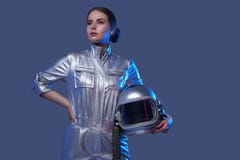 Modern female cosmonaut posing against blue background