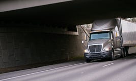 Modern Grey Semi Truck Under Bridge On Interstate Highway Stock Photo Modern Grey Semi Truck Under Bridge On Interstate Highway Stock Photo