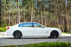 Modern Luxury BMW 750Li XDrive Car Three-quarter Side View Parked On Stone Paved Parking Near Pine Forest Stock Images