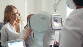 Modern och dottern i ögonläkare`en s hyr rum - optometrikern i klinik som kontrollerar synförmåga för ` s för litet barn arkivfoto Modern och dottern i ögonläkare`en s hyr rum - optometrikern i klinik som kontrollerar synförmåga för ` s för litet barn arkivfoto