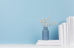 Modern style workplace - white stationery and glass vase with dry flowers on soft blue background and light desk.