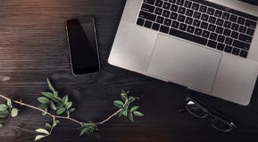 Modern workspace with laptop, mobile phone, eyeglasses and rose branch on wooden background Royalty Free Stock Photos Modern workspace with laptop, mobile phone, eyeglasses and rose branch on wooden background Royalty Free Stock Photos